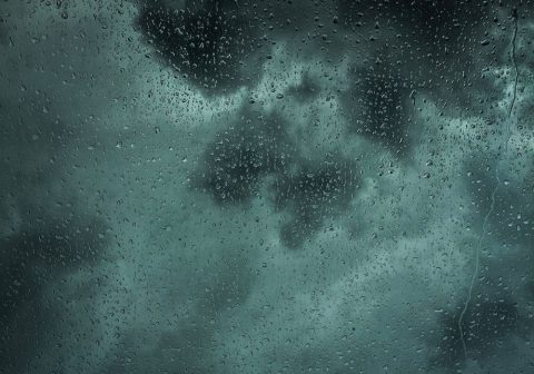 Rain on architectural glass during stormy weather.