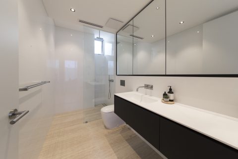 Bright bathroom with a custom frameless glass shower enclosure.