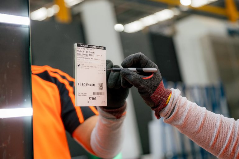 Technician checking specifications on a glass panel inspection tag.