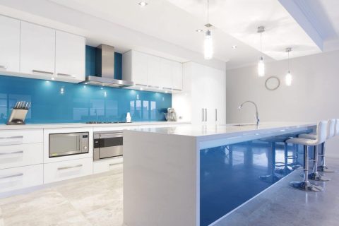 Modern white kitchen with a blue glass splashback.