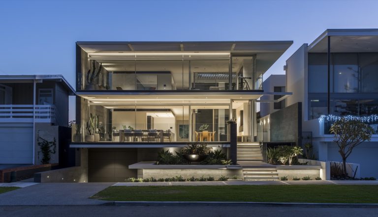 Contemporary glazed home illuminated at dusk.