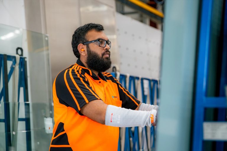 Tough Glass operator positioning a glass panel on the processing line.