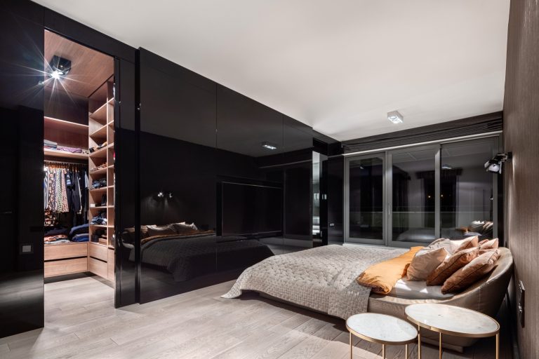 Glossy black glass wardrobe doors beside a walk-in robe