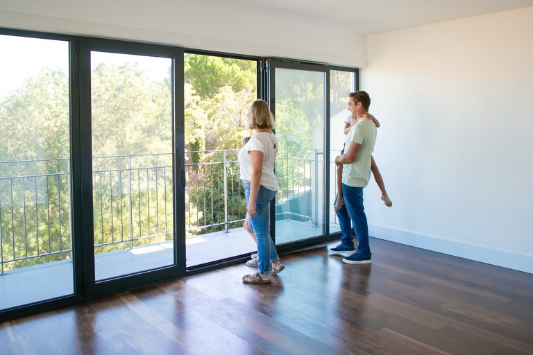 Couple beside floor-to-ceiling double glazed doors in a new home