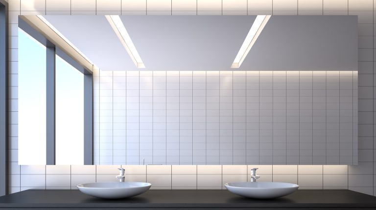 Full-width silver mirror above twin basins in a tiled bathroom