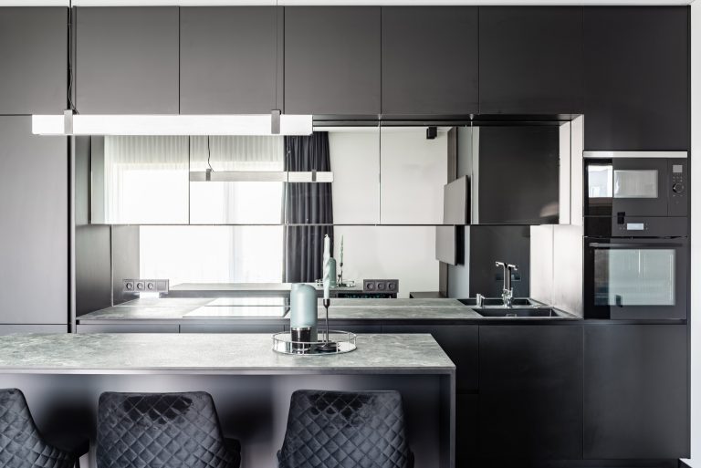 Reflective coated glass splashback catching light behind a kitchen bench