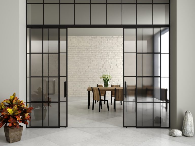 Black steel-framed tinted glass doors opening to a dining room