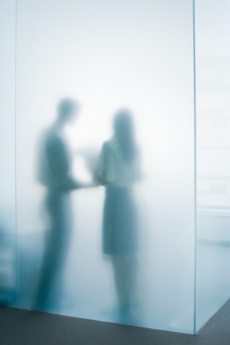 Switchable privacy glass turned opaque, softly obscuring an office meeting