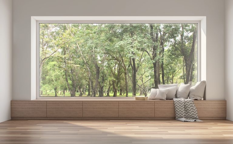 Full-width low-iron window framing a leafy garden view from a window seat