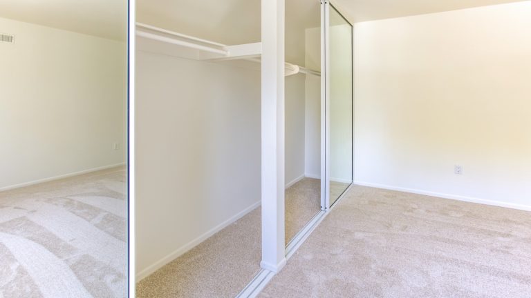 Mirrored sliding wardrobe doors with vinyl backing in a bedroom