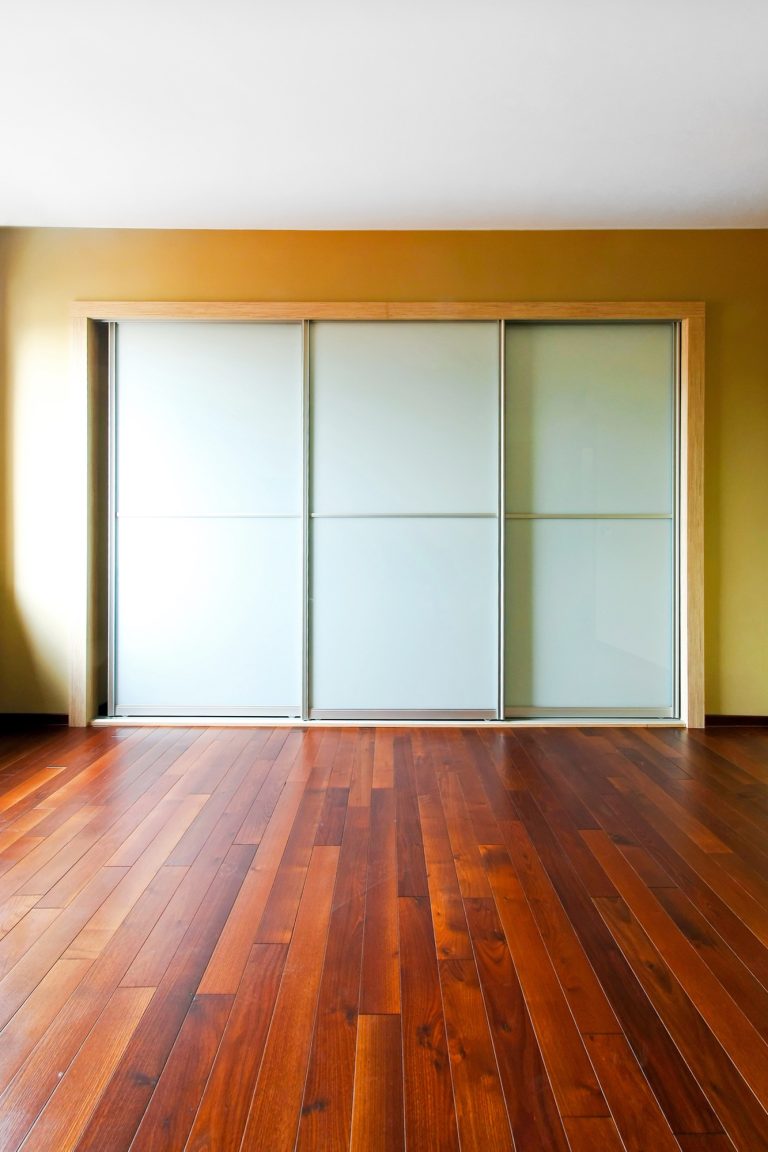 White vinyl backed glass wardrobe doors on rich timber flooring